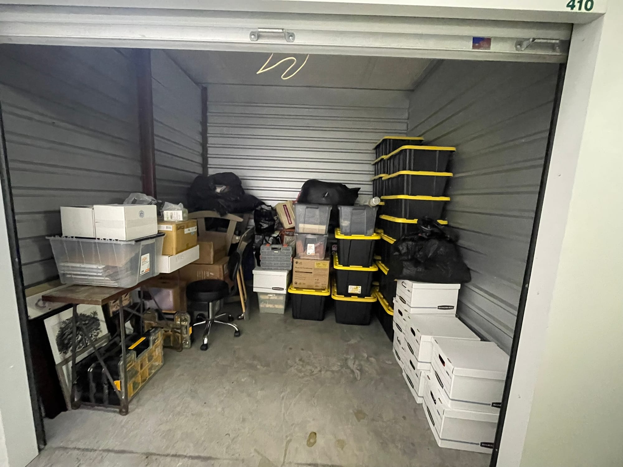 Climate-controlled storage unit filled with organized boxes, bins, and belongings stacked along the walls.