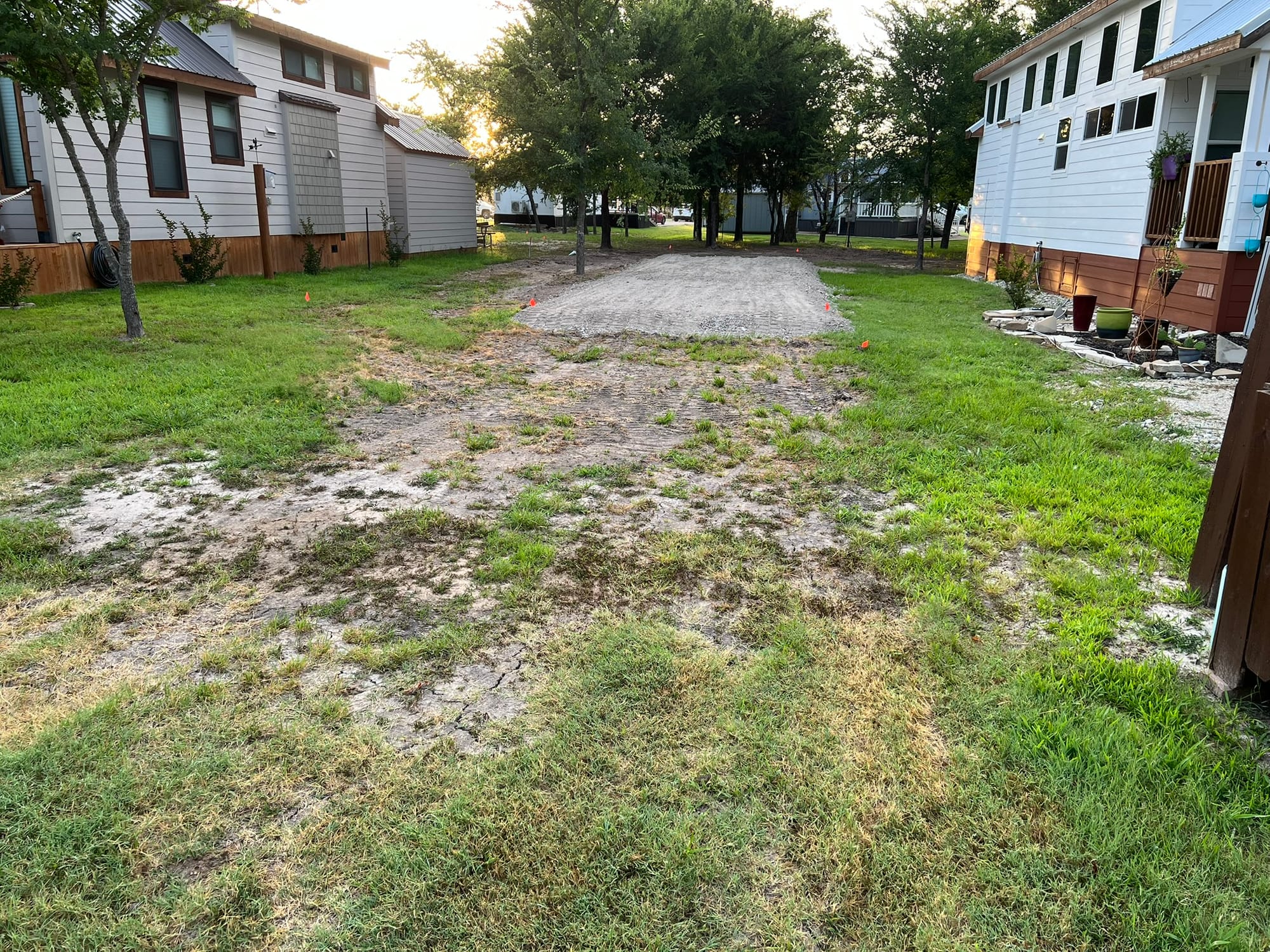 Tiny home pad with gravel foundation, trees in background, space for carport and storage unit
