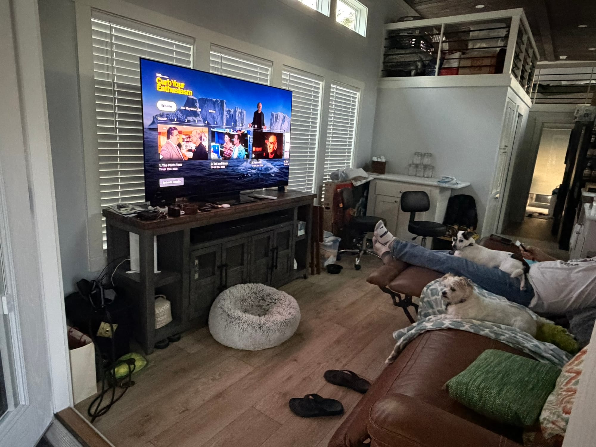 Organized tiny house living room with mounted TV, clean couch, and functional layout showing completed transformation