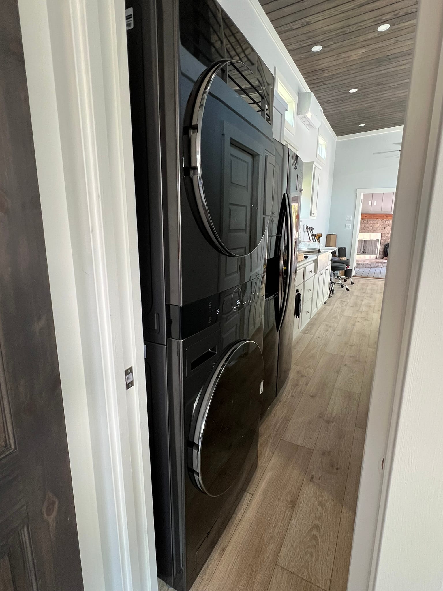 Stacked washer and dryer units protruding into hallway of tiny house, showing space constraint compromise