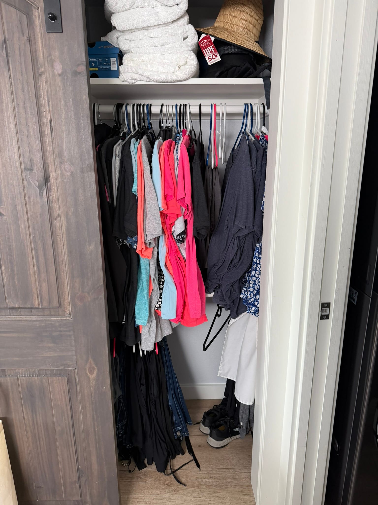 Open barn-style closet door showing clothes hanging inside