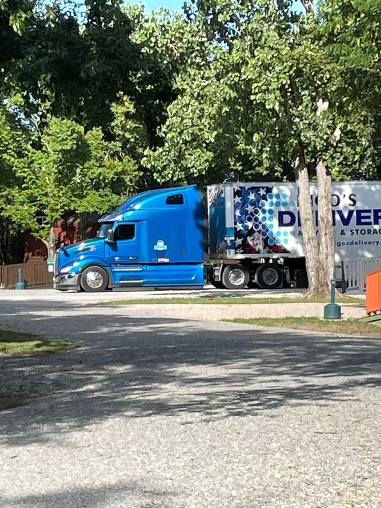 Blue semi truck with delivery trailer parked on street outside tiny home community
