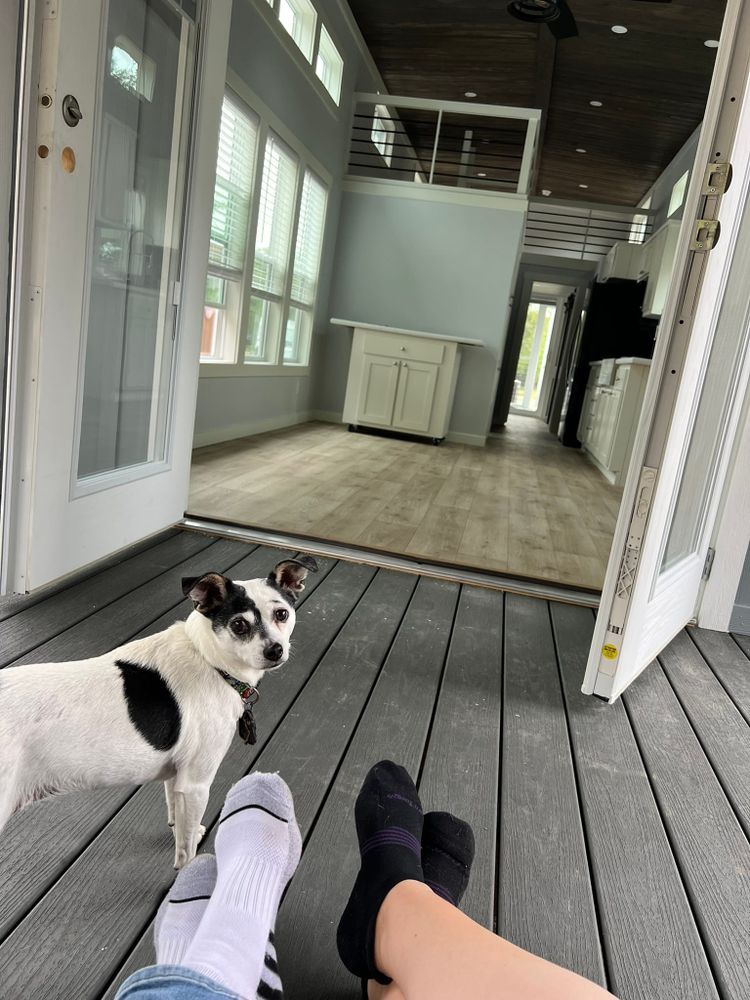 View from screened porch showing feet resting while looking through open French doors into tiny house living room