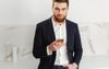 Real Estate Agent Keeps Match Fit By Playing On Phone While Leaning On Bench Top In Kitchen