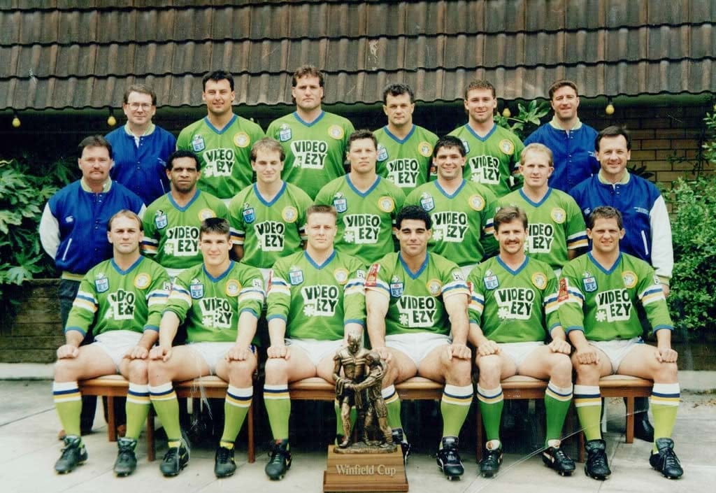 1990 Grand Final Winners: Lazarus sits next to co-captain Mal Menings (current QLD coach) while Laurie Daley (current NSW coach) sits in the back left. Current Raiders coach Ricky Stuart sits back right.