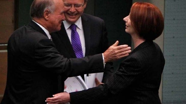 Julia Gillard embraces Independent MP Tony Windsor as Kevin Rudd looks