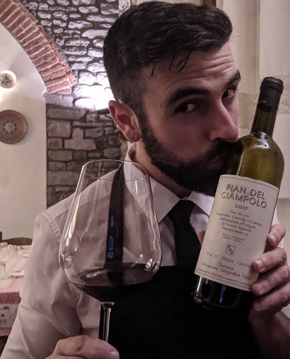 Francesco, The Italian Sommelier, al lavoro in sala con una bottiglia di Pian del Ciampolo in un ristorante in Toscana