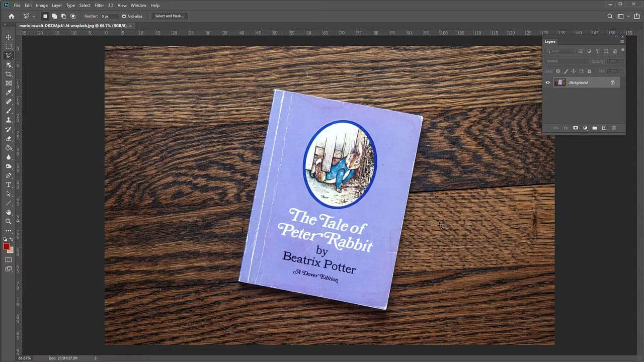 A perspective-distorted photo of a book on a dark wooden table open in Photoshop