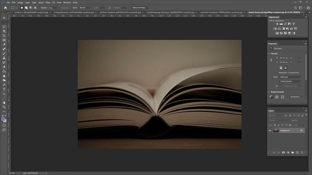 A dark underexposed photograph of an open book open in Photoshop before any corrections