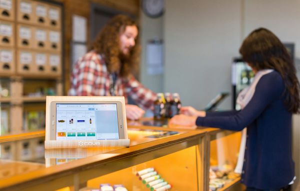 Predavač obsluhuje zákazníčku pri pulte v predajni s kanabinoidnými produktmi