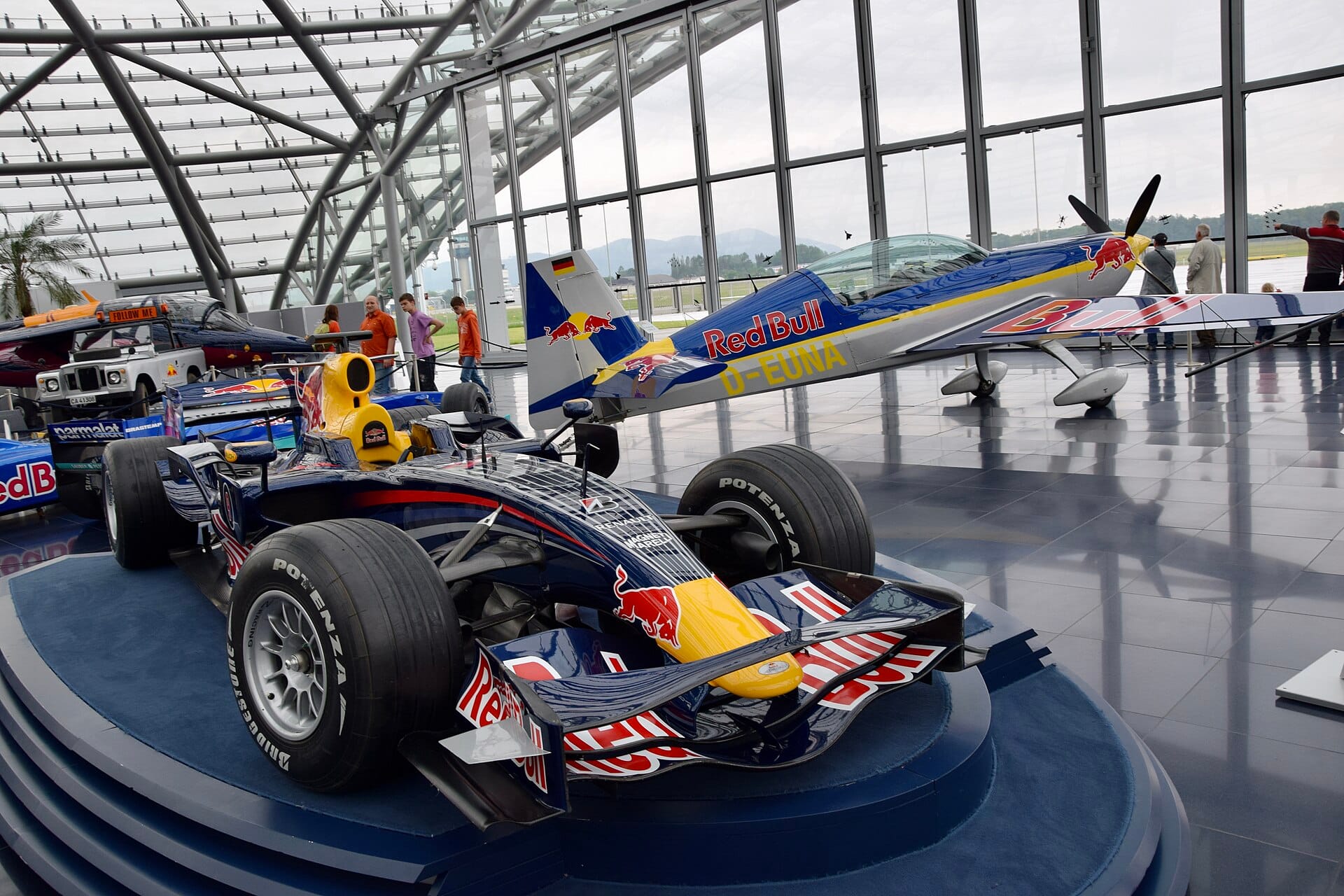Red Bull Racing Formula One car and aerobatic plane inside Hangar-7 glass facility.