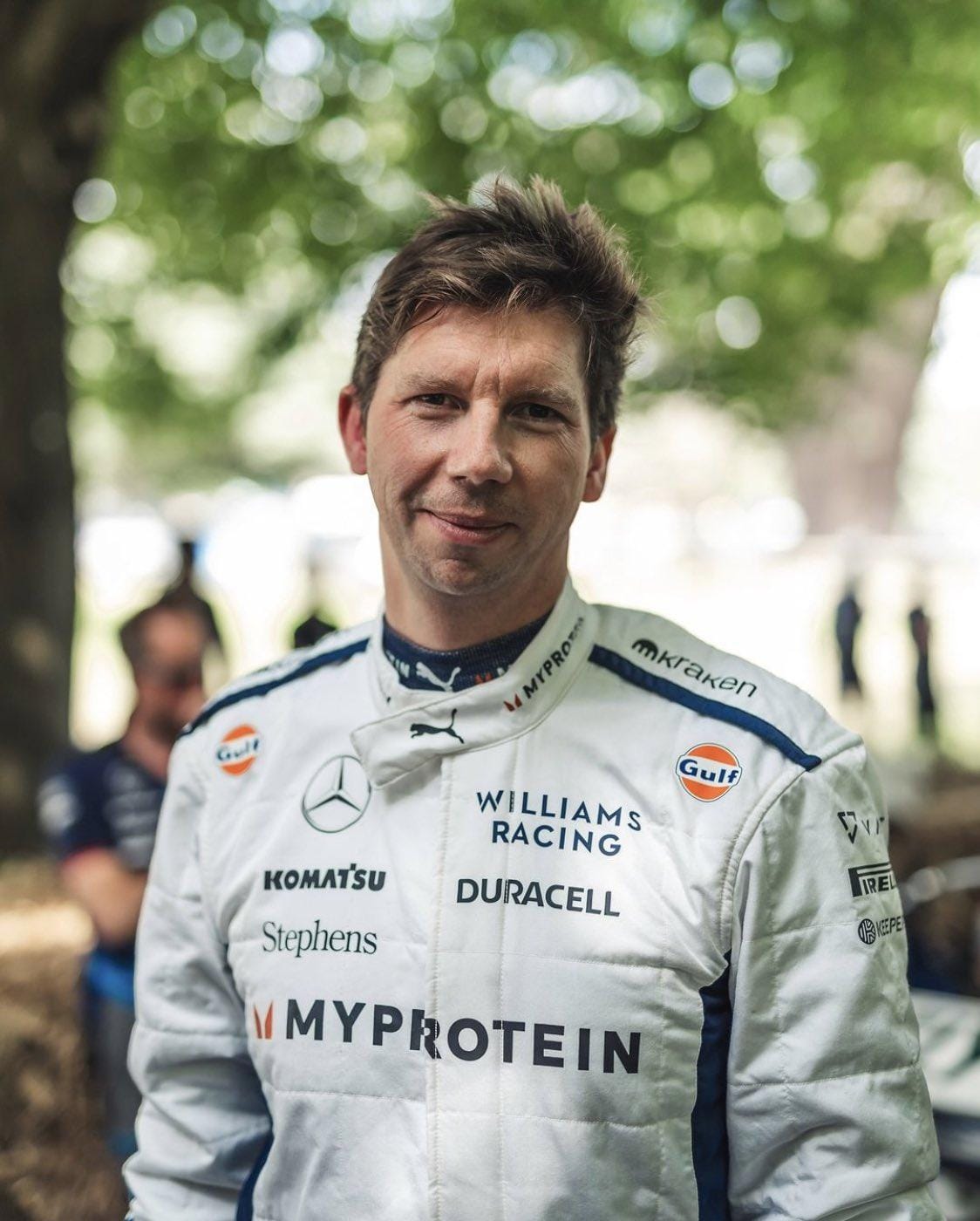 A medium close-up portrait of Williams Racing team principal James Vowles in a white racing suit outdoors.