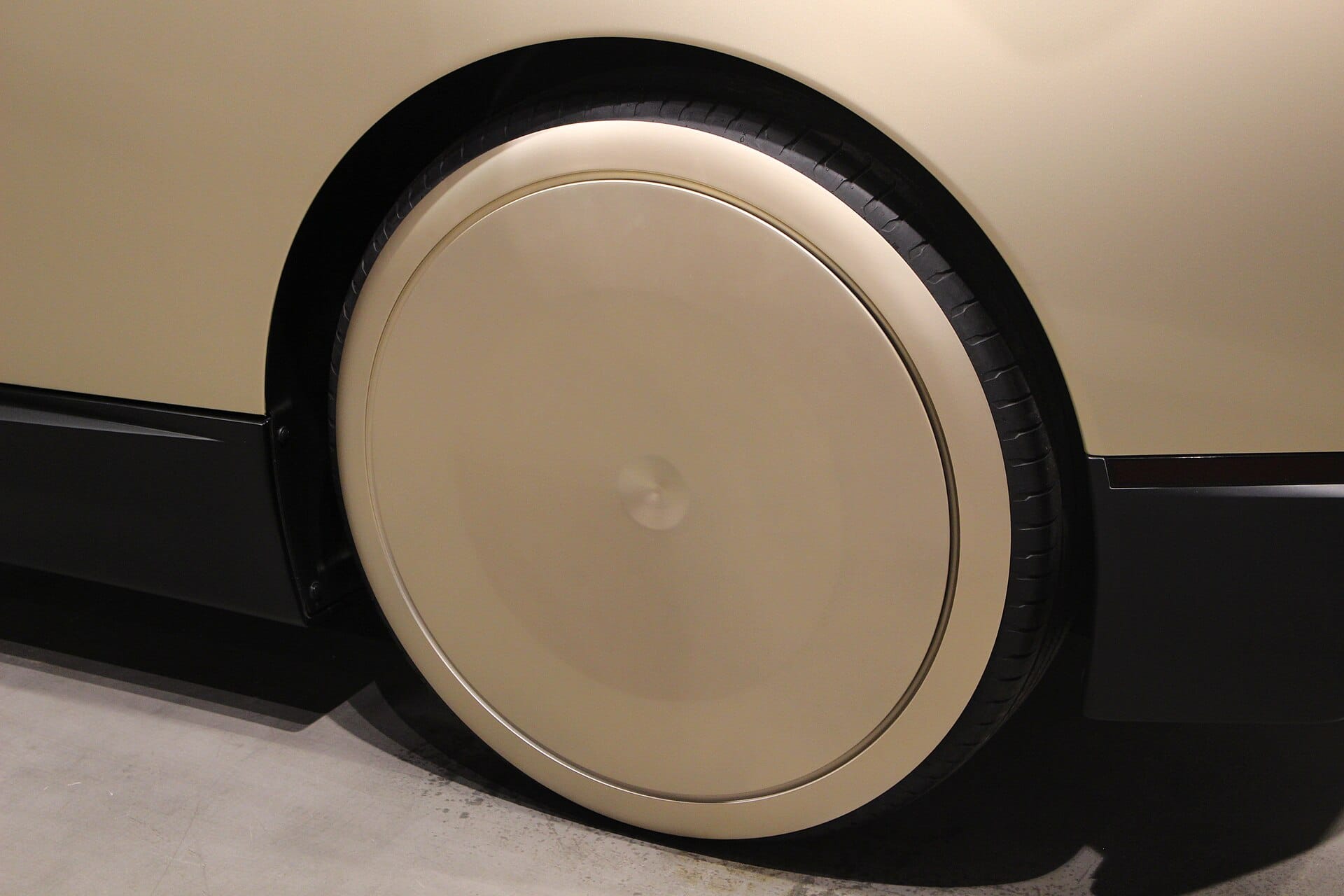A close-up side profile shot focusing on the smooth, gold-colored aerodynamic wheel cover and wheel of a Tesla Cybercab.
