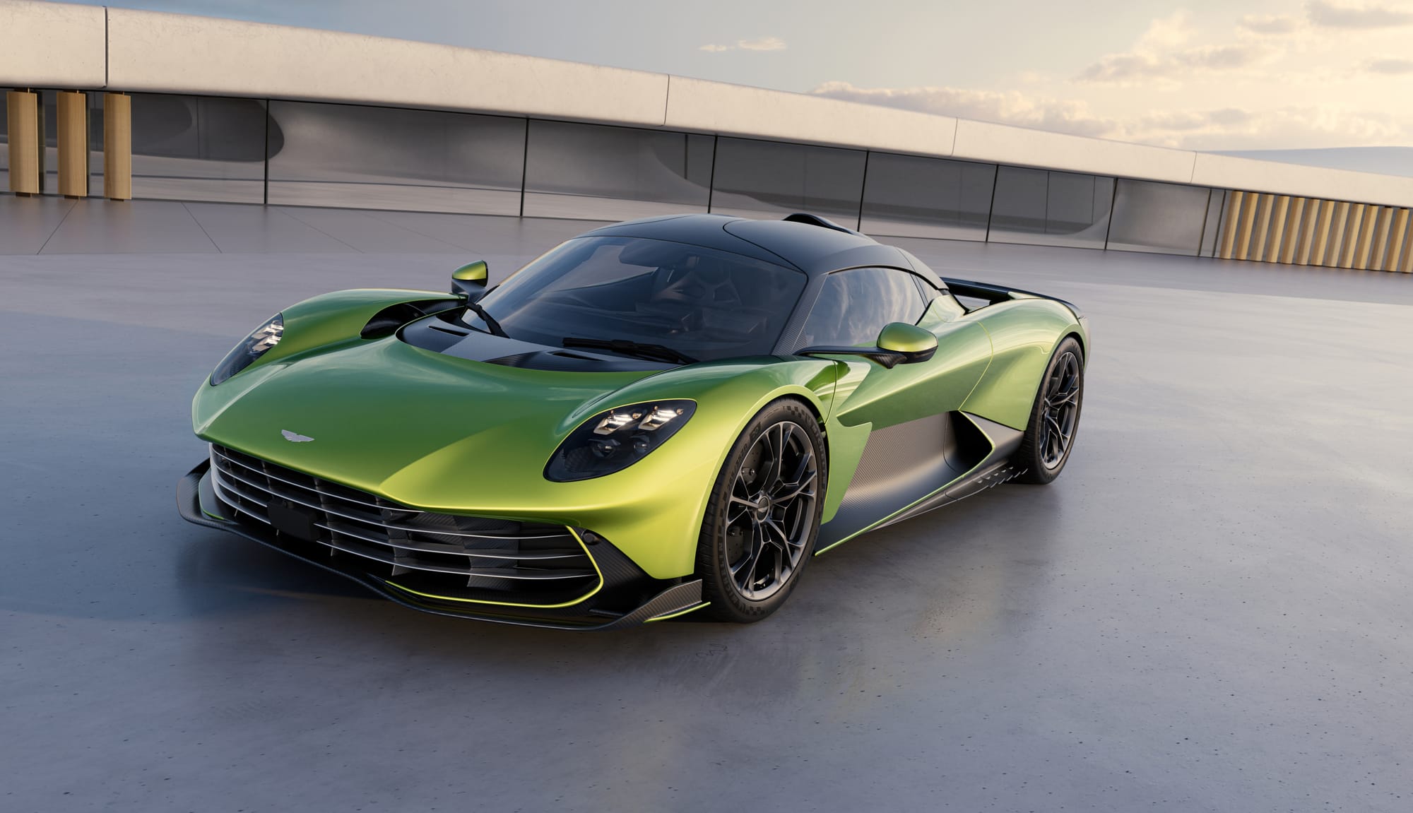A metallic green Aston Martin Valhalla supercar parked outside a modern minimalist structure under daylight.