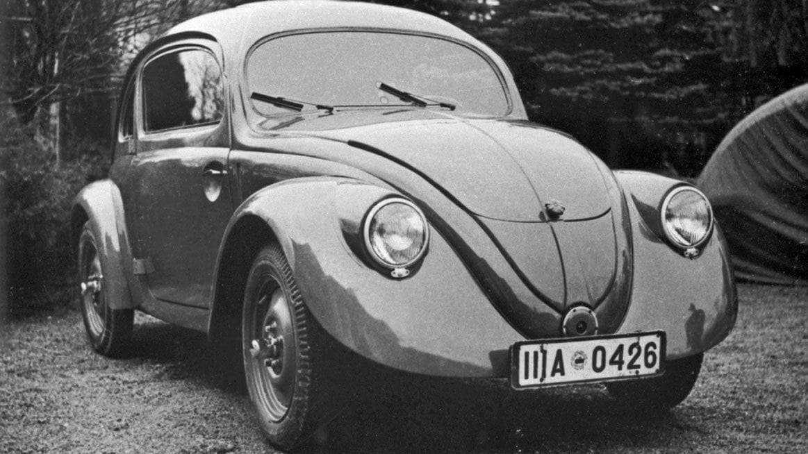 A vintage black and white photograph of a classic early Volkswagen Beetle prototype or production car parked outdoors, viewed from the front three-quarters angle with a license plate reading IIIA 0426.