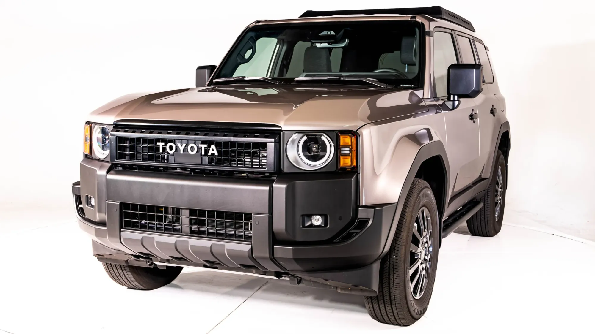 A studio shot of a modern bronze Toyota Land Cruiser 1958 trim featuring round headlights and a heritage TOYOTA grille against a plain white studio background.
