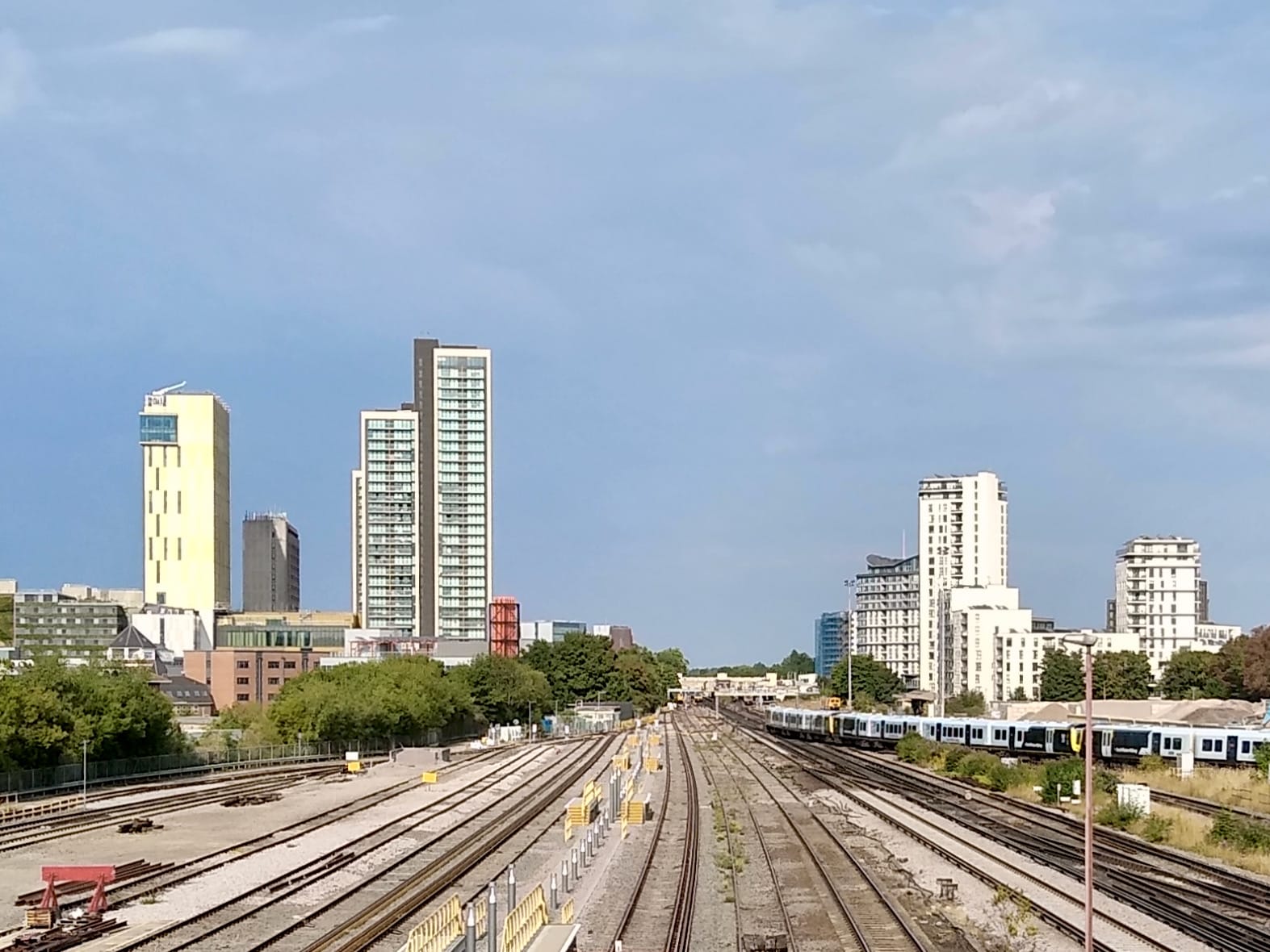 View of the townscape of Woking with railway tracks leading into the station and modern high-rise buildings in the background.