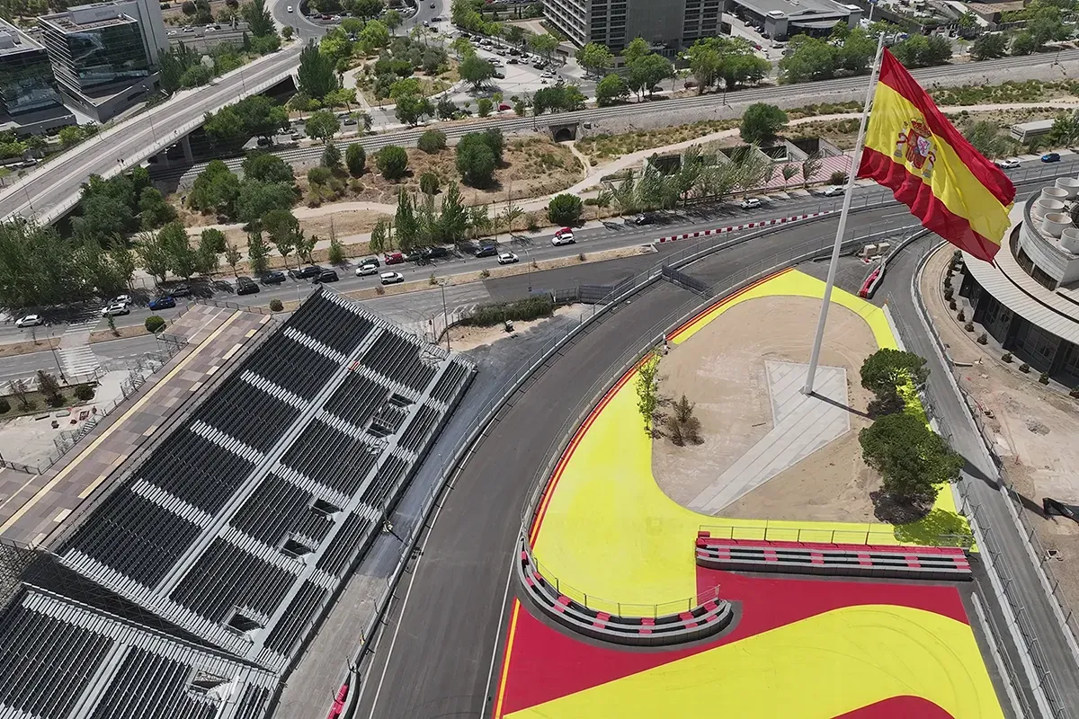 An overhead view of the Madrid street circuit being built for the Spanish Grand Prix, featuring a section of the track painted in the colors of the Spanish flag and a large Spanish flag on a pole.