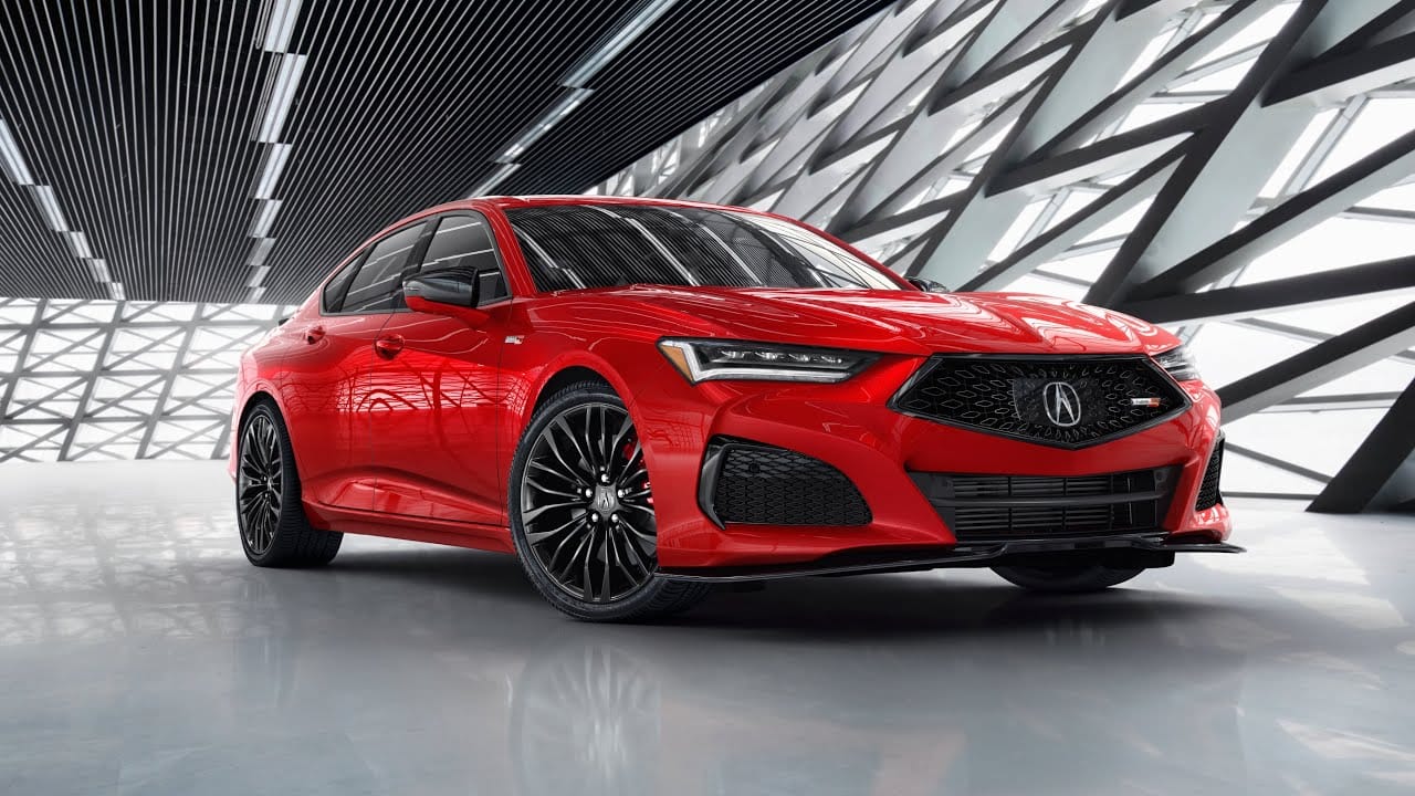A red Acura TLX Type S sports sedan parked inside a modern showroom featuring geometric lattice wall patterns.