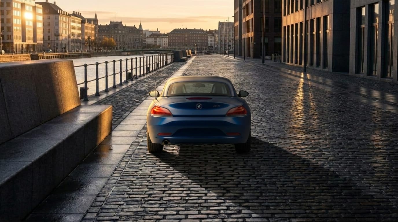 En mörkblå BMW Z4 står parkerad på en kullerstensgata under gyllene timmen med långa skuggor.