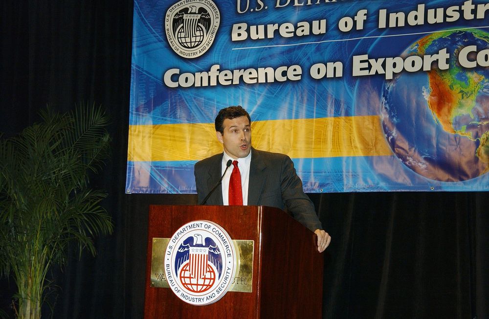 A speaker delivering a speech at a Bureau of Industry and Security conference behind a branded podium.