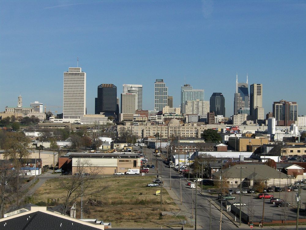 A wide shot of the Nashville skyline showing various downtown skyscrapers and buildings under a clear blue sky.