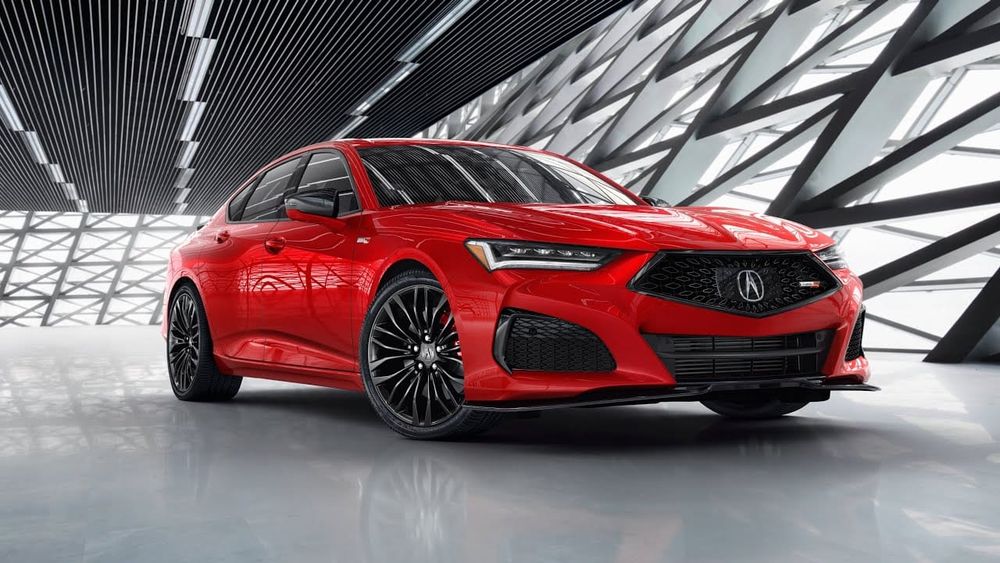 A red Acura TLX Type S sports sedan parked inside a modern showroom featuring geometric lattice wall patterns.