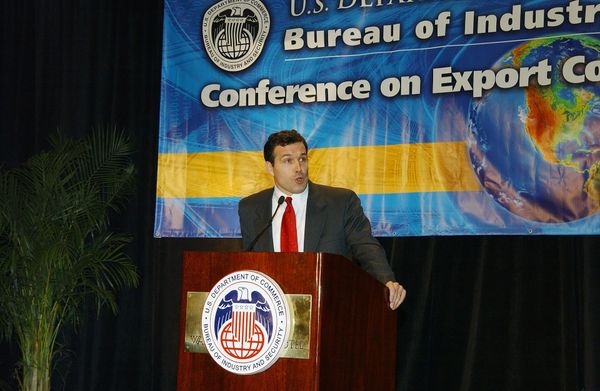 A speaker delivering a speech at a Bureau of Industry and Security conference behind a branded podium.
