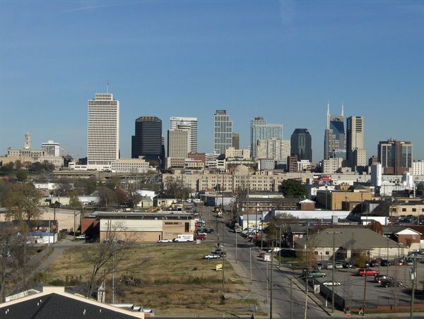 A wide shot of the Nashville skyline showing various downtown skyscrapers and buildings under a clear blue sky.