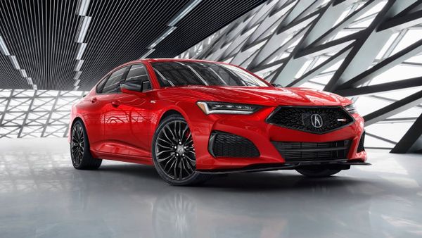 A red Acura TLX Type S sports sedan parked inside a modern showroom featuring geometric lattice wall patterns.