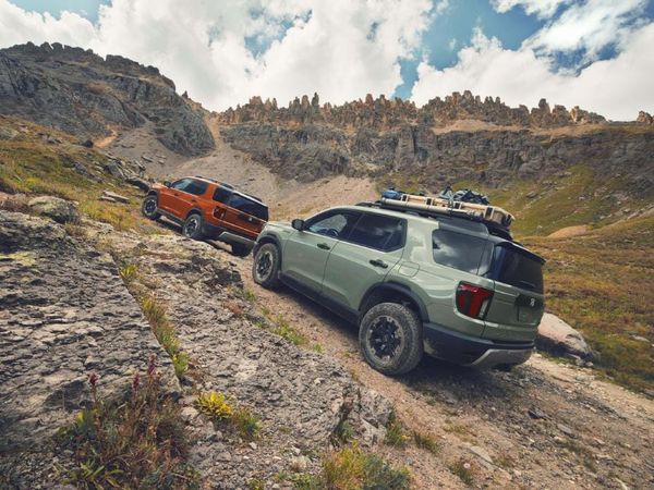 Two Honda Passport TrailSport SUVs driving up a rocky mountain trail in an adventurous outdoor setting.