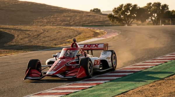 Formulabil som svänger i en kurva på en asfaltbana i eftermiddagsljus.