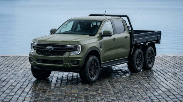 Militärgrön sexhjulig Ford Ranger-prototyp parkerad på en stenhäll vid vatten.