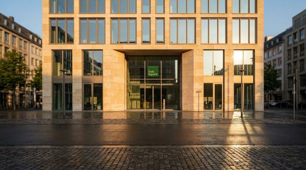 Fasad av glas och sten till Park Square Capitals huvudkontor, tagen i klart dagsjus från gatuplan.