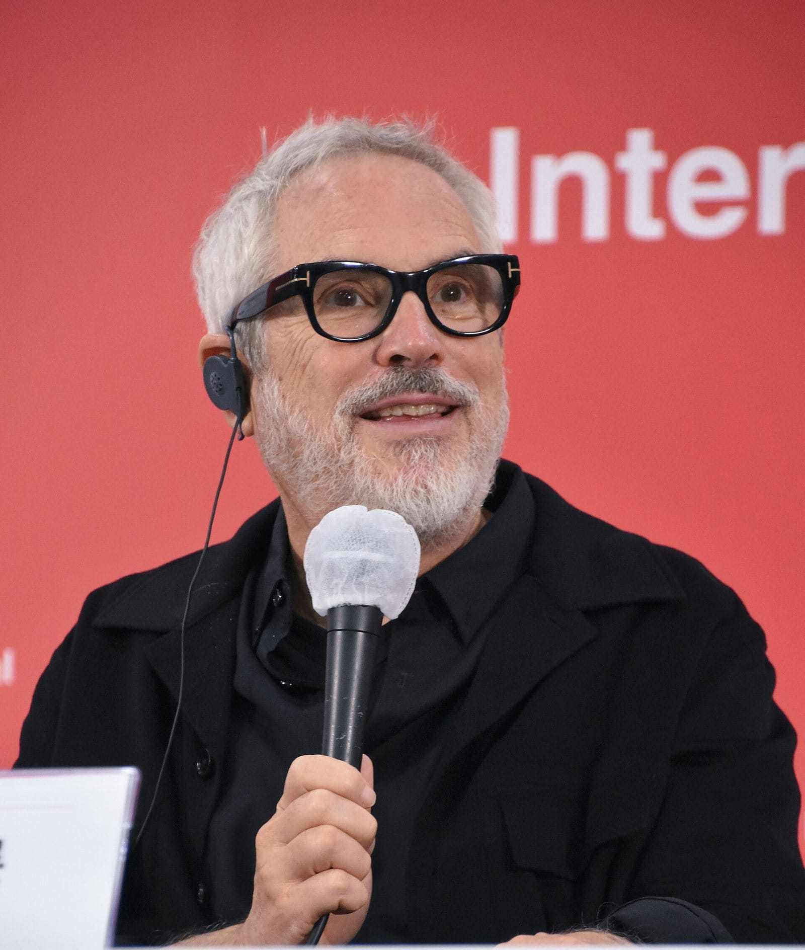 Alfonso Cuarón speaking into a microphone at the Busan International Film Festival