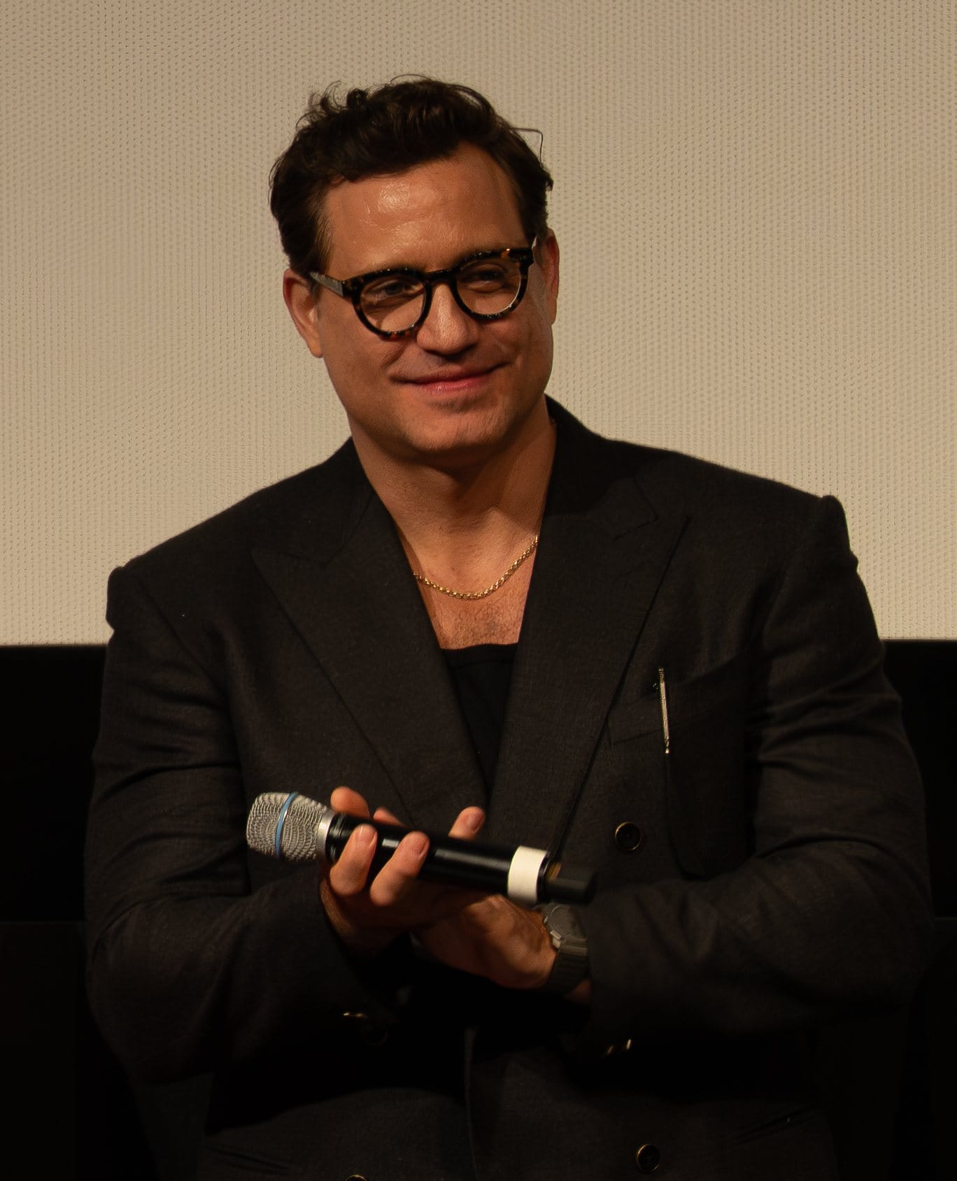 Edgar Ramírez in glasses holds a microphone during a Q&A