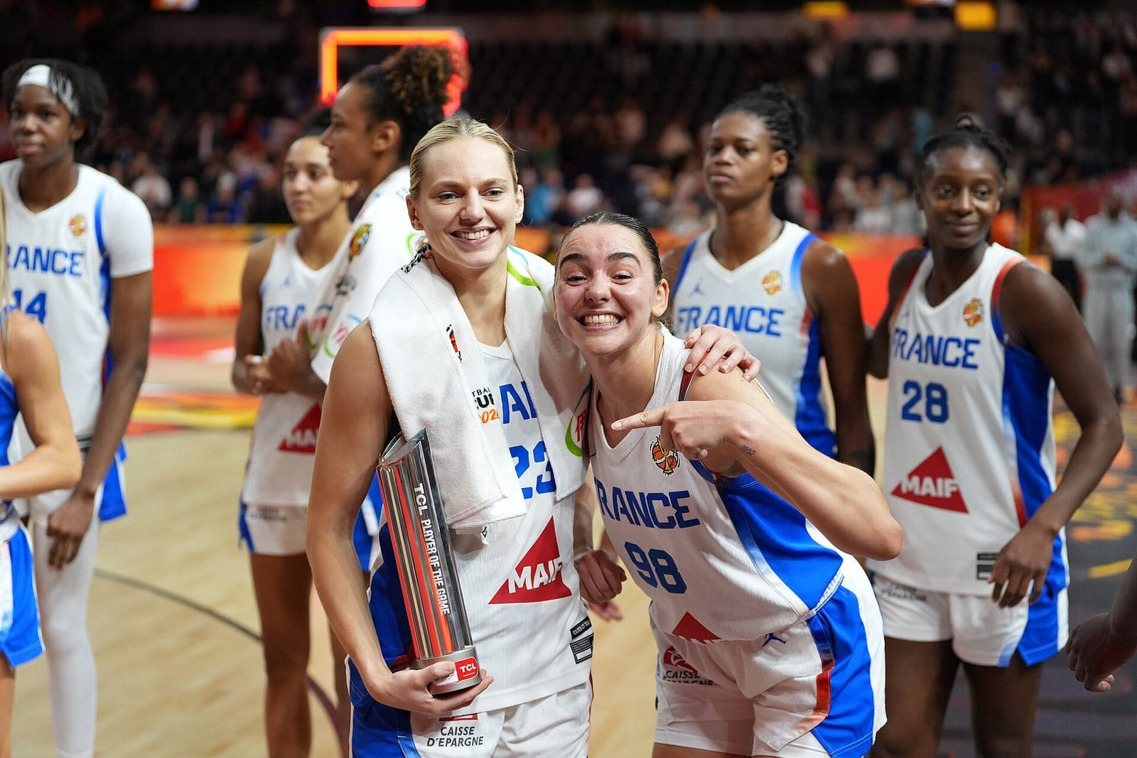Marine Johannès and a France teammate smile courtside in their white France jerseys