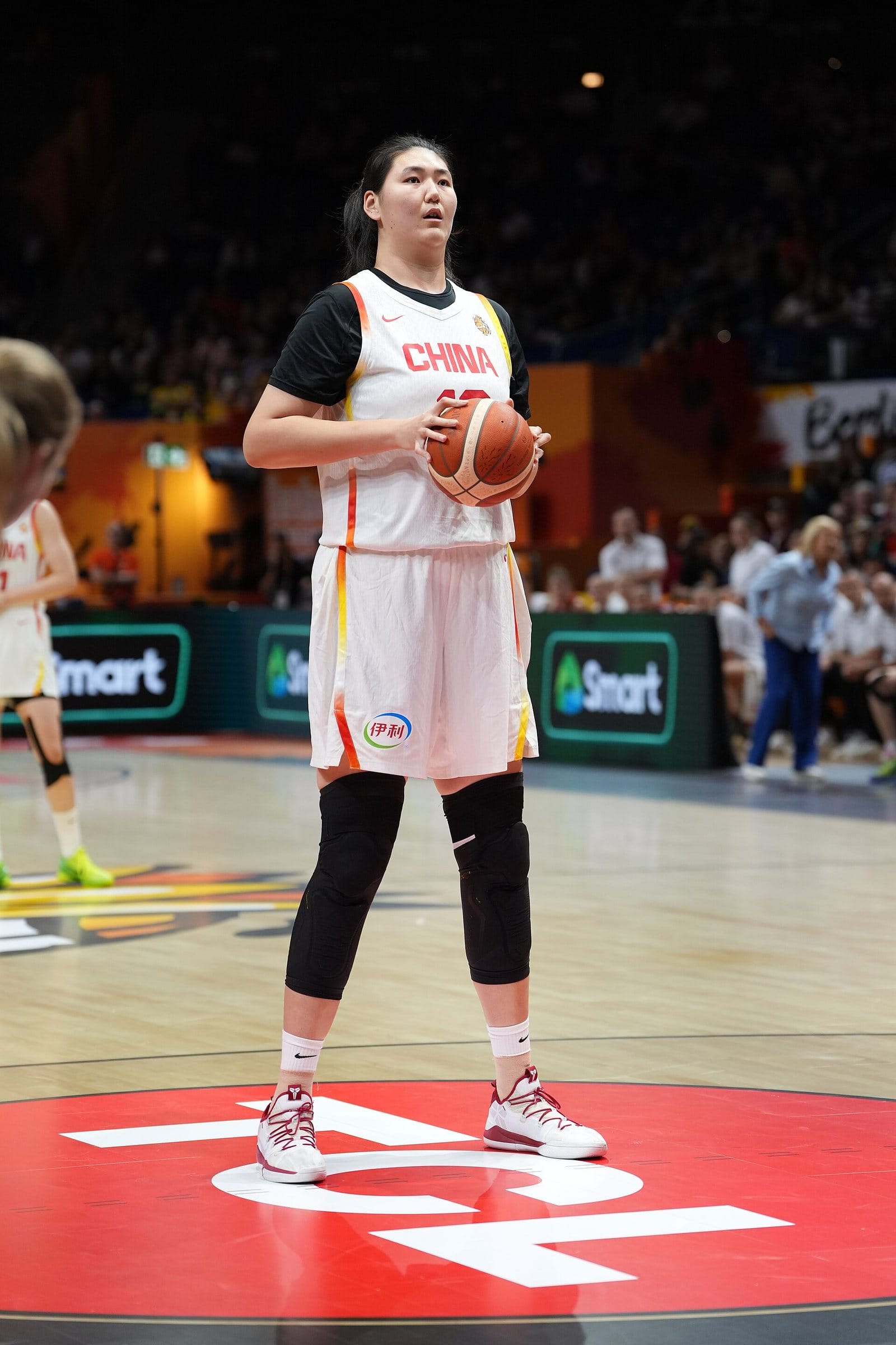 Zhang Ziyu of China stands on court in her white China uniform, holding a basketball
