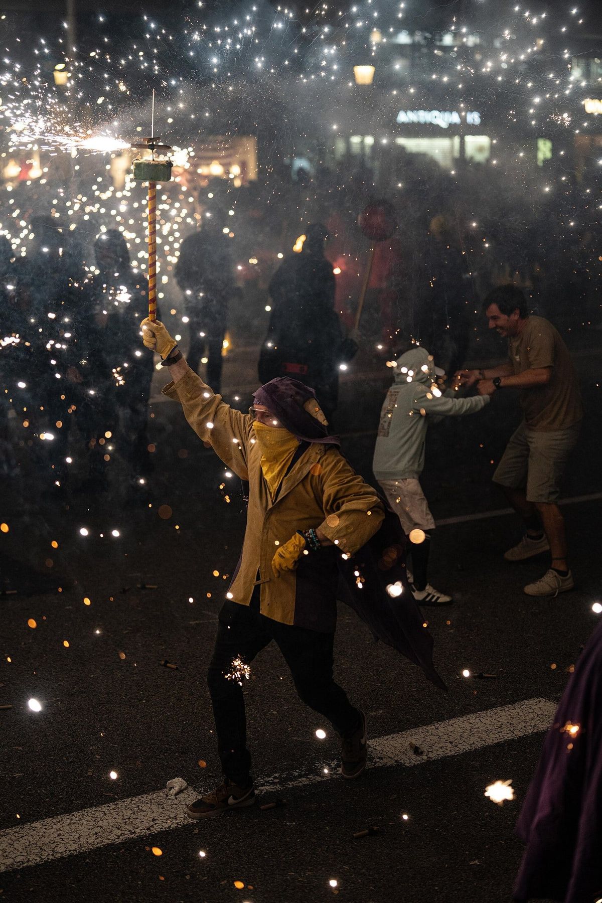 A fire devil swings a spray of sparks through the crowd at night during the Correfoc in Barcelona