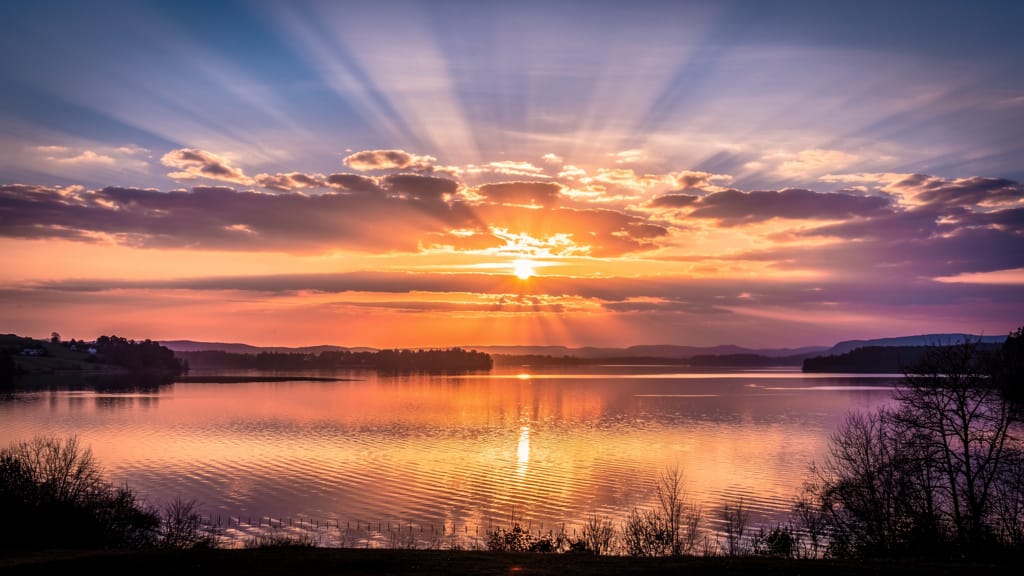 A golden sunrise breaks over a calm lake, its light rays reflecting across the water, generated with Flux 2 Pro text to image on Eachlabs.