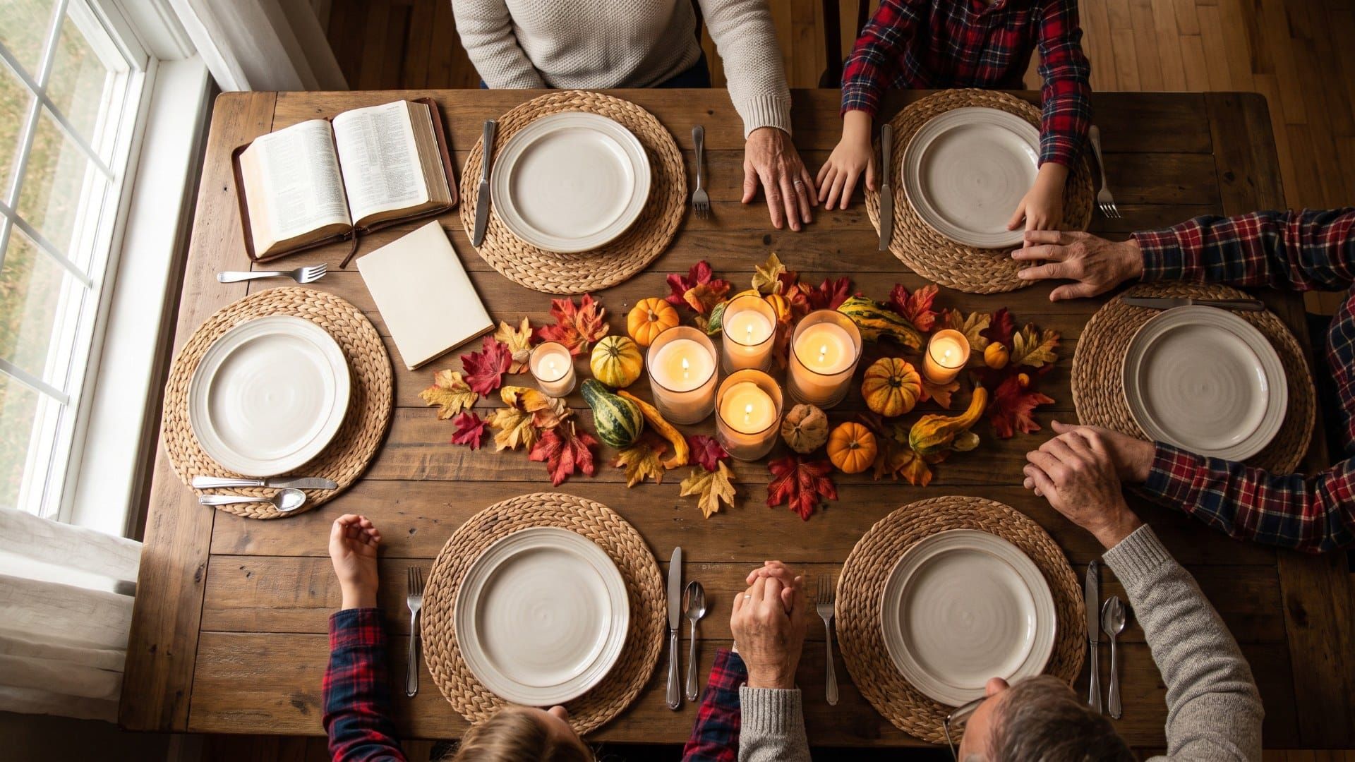 Overhead view of a family Thanksgiving table with an open Bible and a printed devotional booklet among autumn decorations