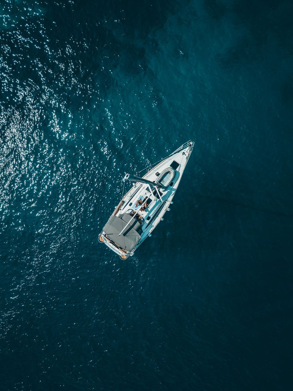 Aerial view of a white sailing yacht underway in deep blue Caribbean water