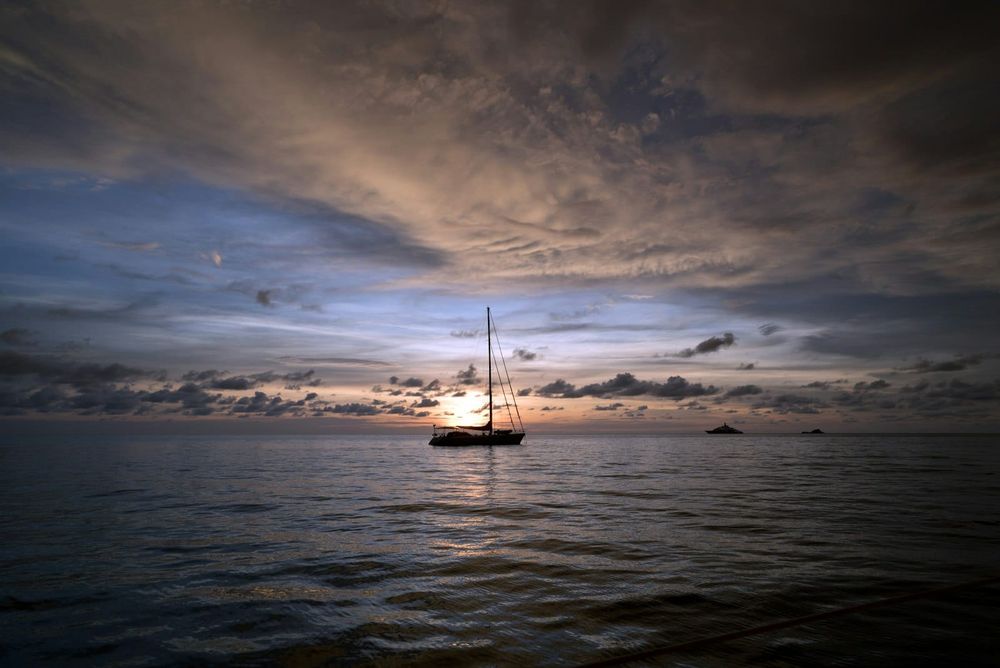 Sailboat silhouette under moody storm clouds