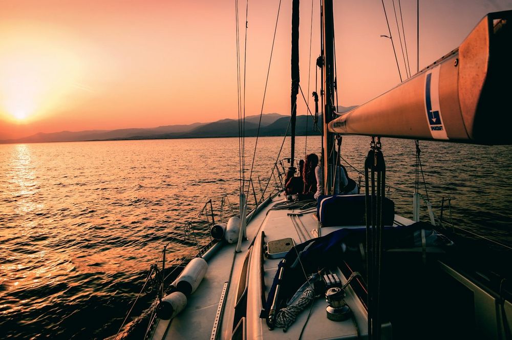 Side deck of a sailboat at sunset, sailing toward open water