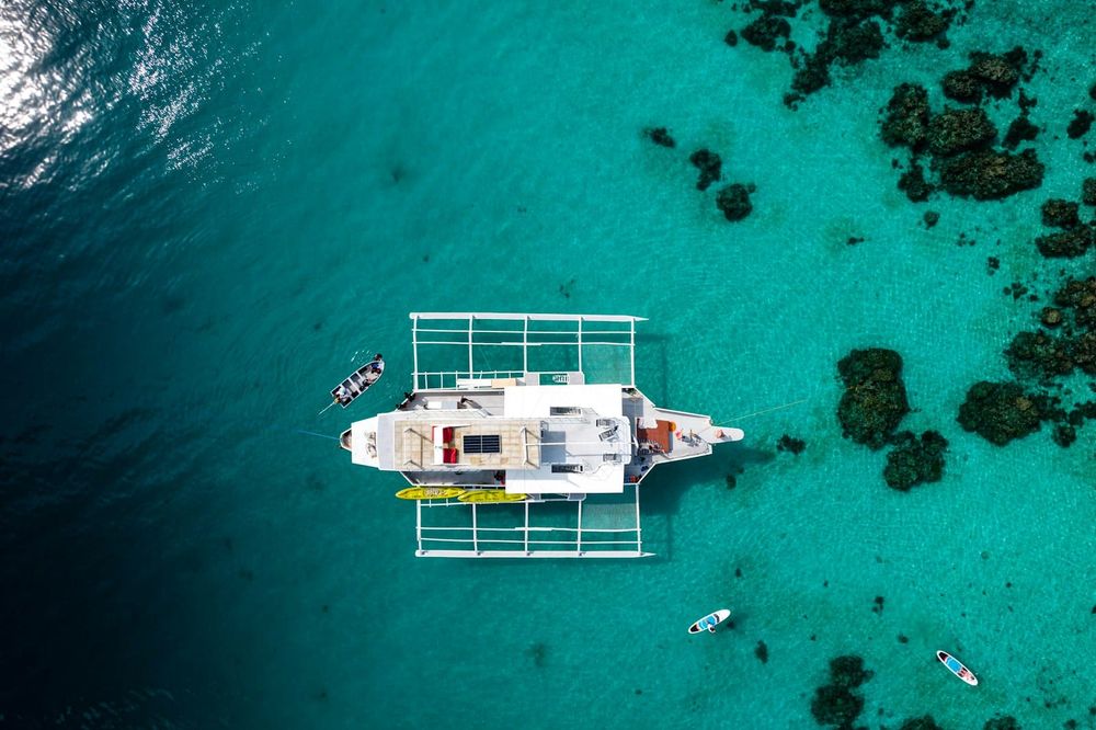 Catamaran anchored in clear turquoise water — the kind of anchorage where a house bank does its real work