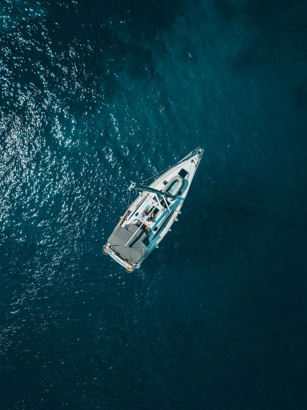 Aerial view of a white sailing yacht underway in deep blue Caribbean water