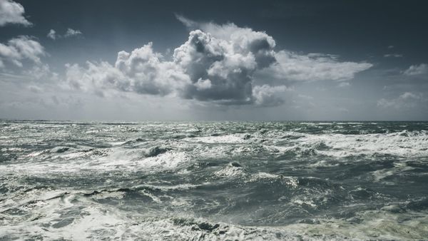 Rough sea with breaking white caps under heavy gray storm clouds