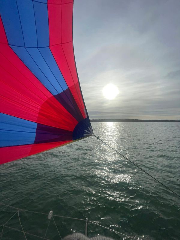 Sailboat flying red spinnaker under bright sun