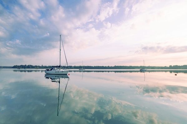 Sailboats lying to anchor at dawn with mirror calm reflections