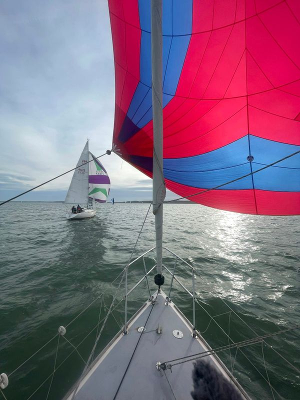 Sailing yacht cockpit view with spinnaker flying and a second yacht in the distance